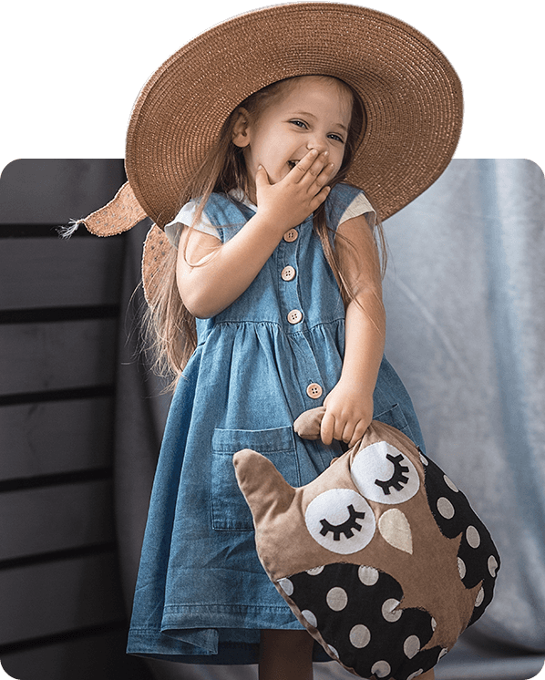 A little girl in a hat holding an owl bag