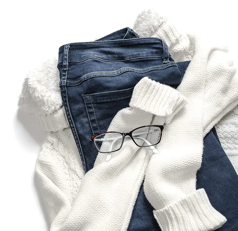 A pair of glasses and some white socks on top of jeans.
